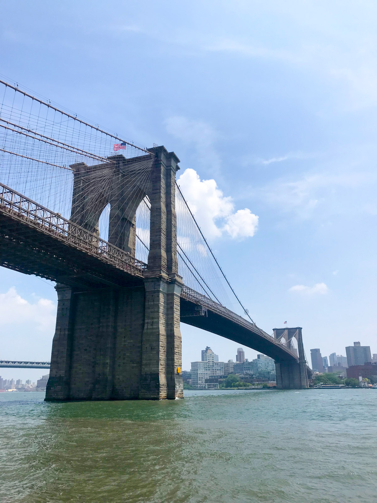 A low angle shot of a large bridge with concrete pillars, with murky green water visible underneath