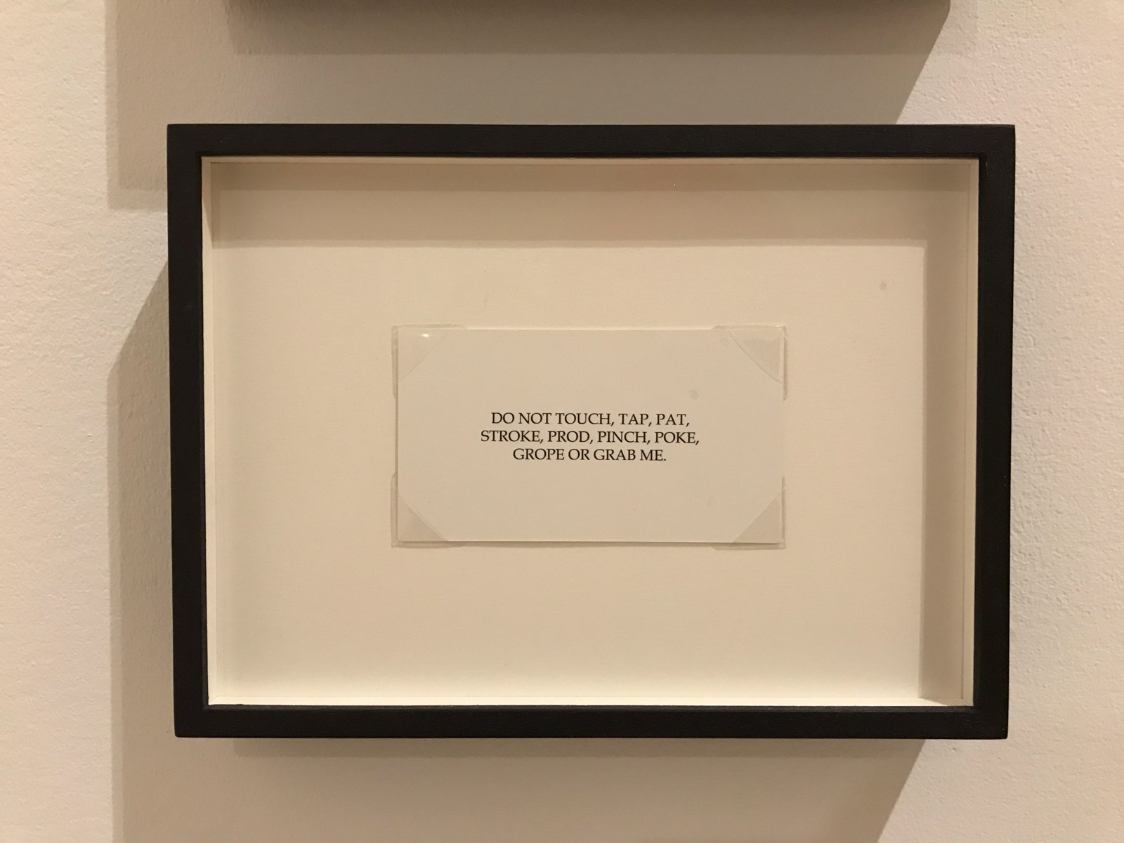 A framed white card reading: “Dear Friend, I am not here to pick anyone up, or to be picked up. I am here alone because I want to be here, ALONE. This card is not intended as part of an extended flirtation. Thank you for respecting my privacy.”