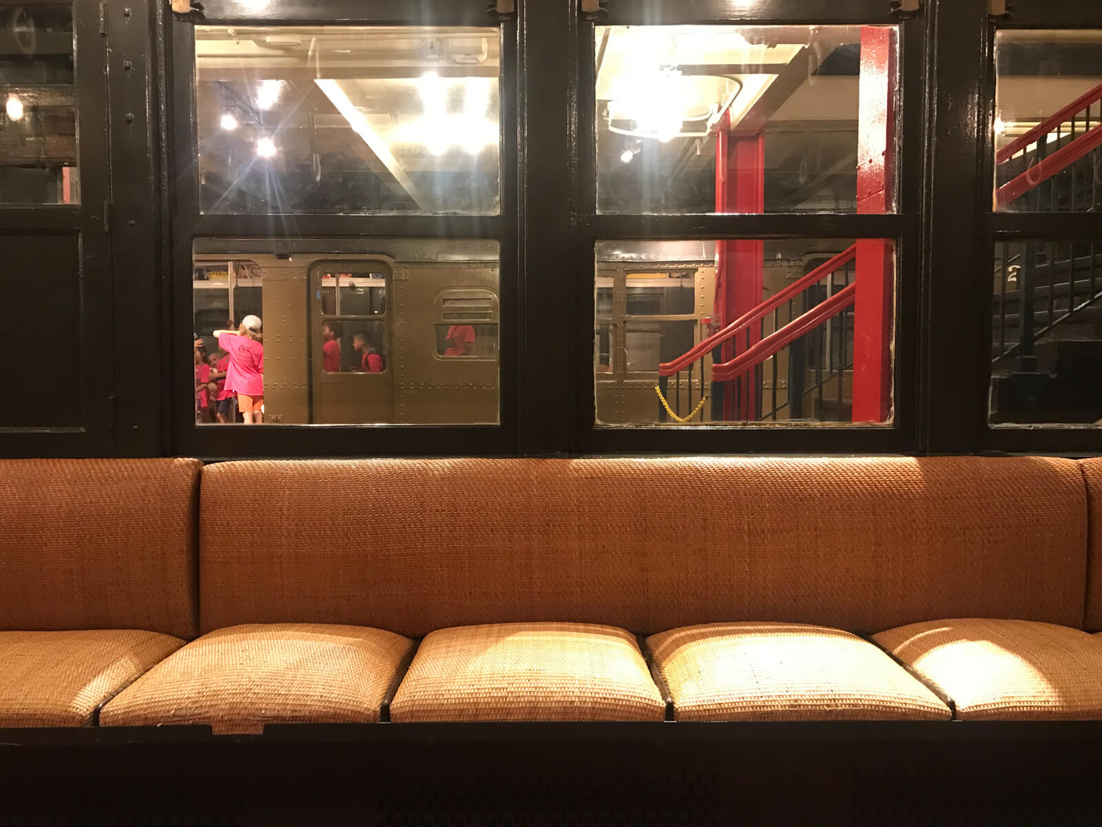 The inside seating of a retired train carriage, looking out onto the platform