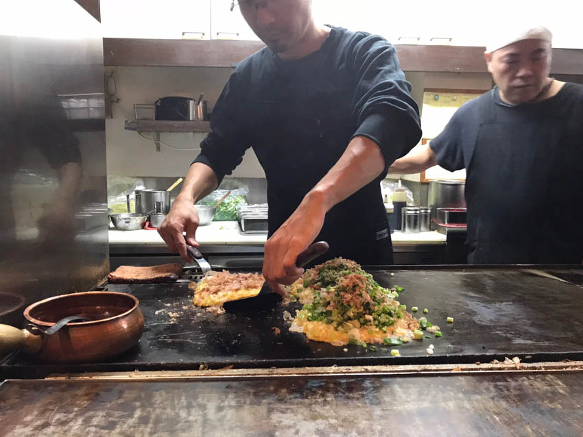 Chefs creating okonomiyaki on the hot stove