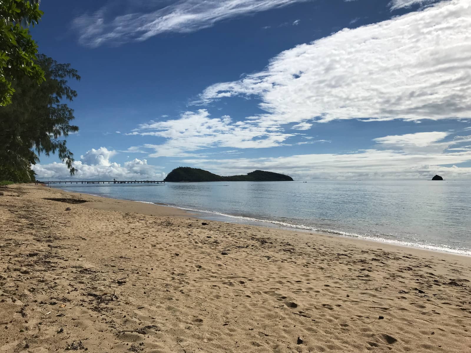 A view of a beach looking partially out to the water. There is a boardwalk in the distance