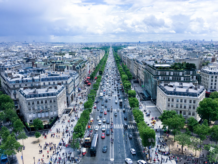 Street view of lots of cars and traffic, taken from the top of the Arc de Triomphe