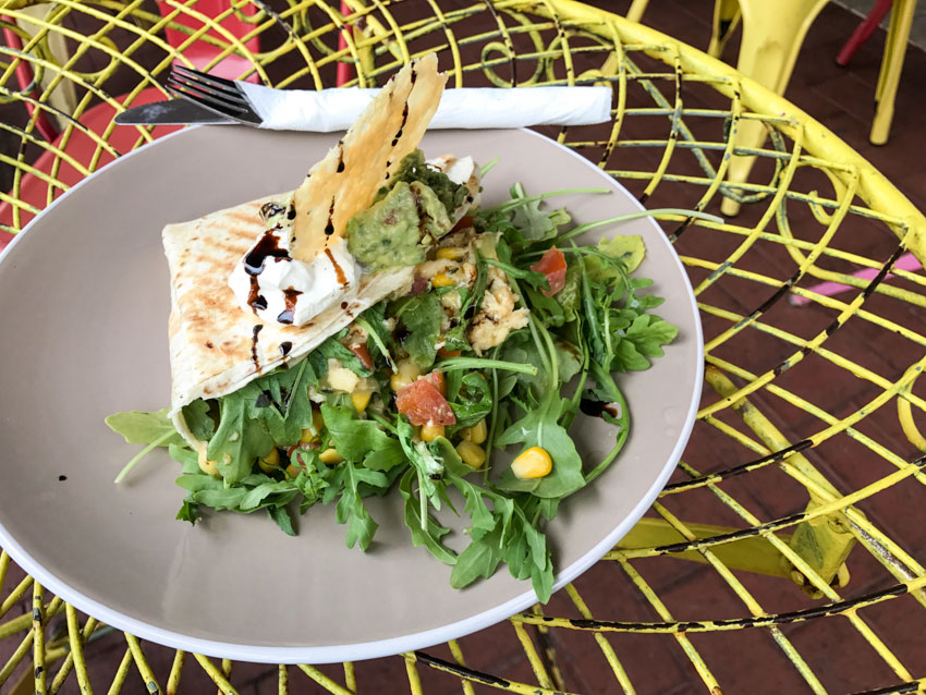 Breakfast quesadilla on a plate, filled with corn, tomato, rocket and cheese