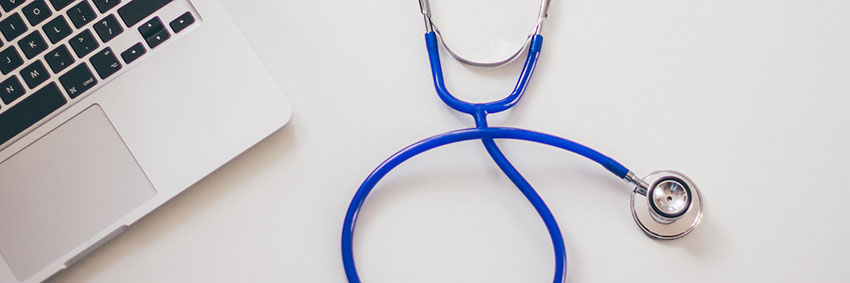 MacBook and stethoscope on a table