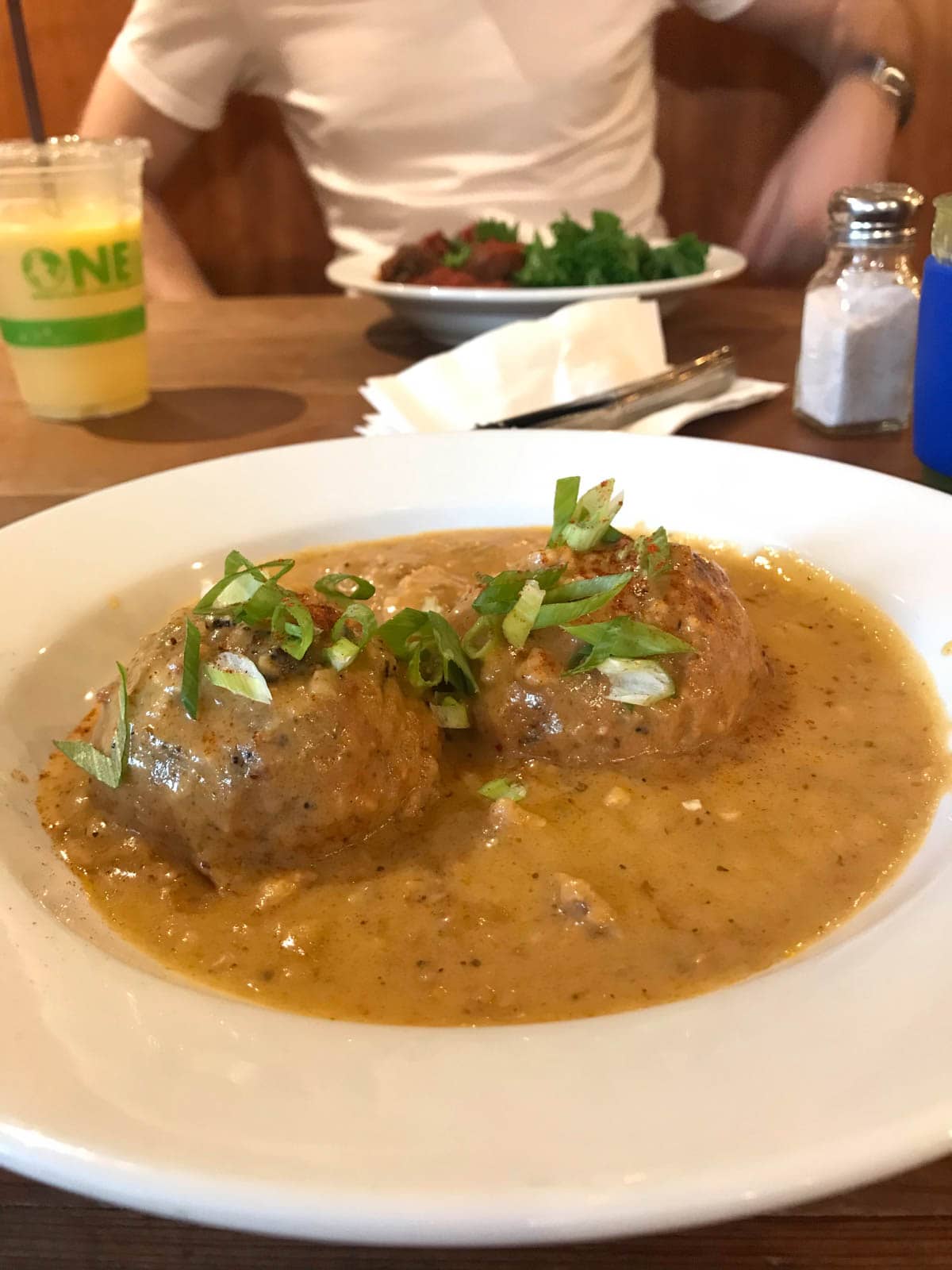 A plate of brown curry-like soup with vegetarian meatballs.