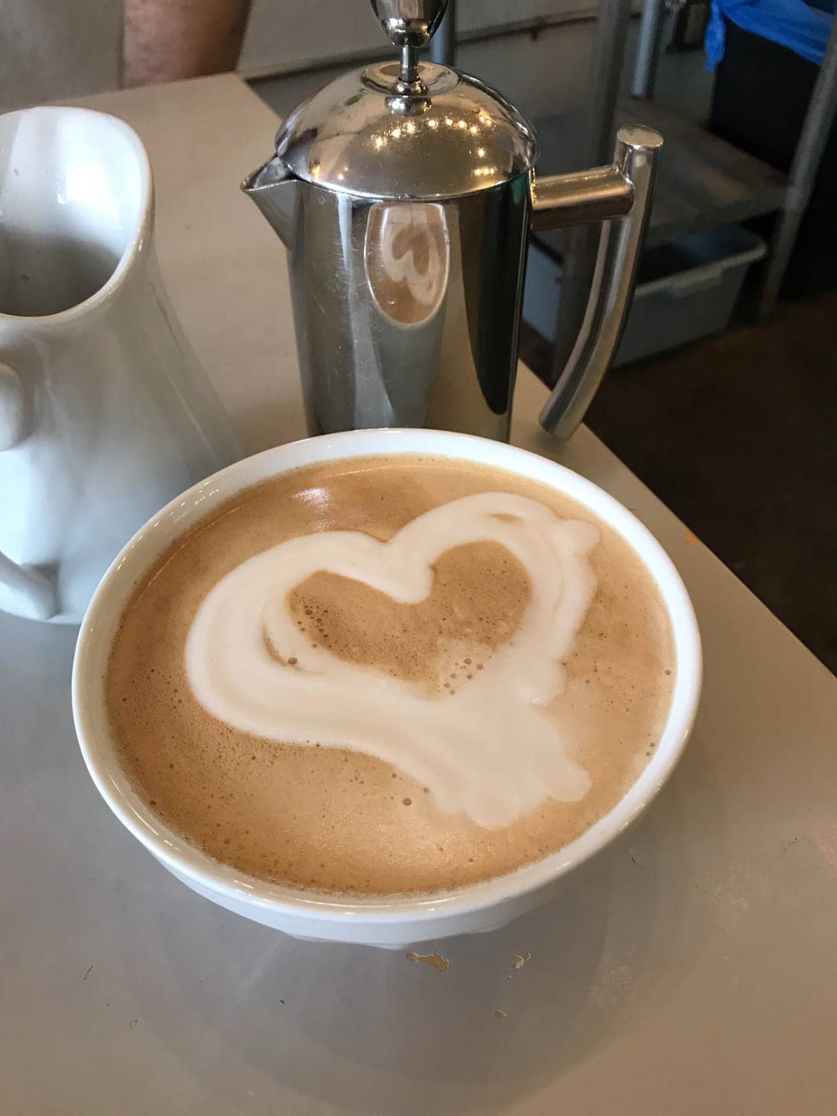 A cup of French pressed coffee with milk, with the milk froth forming a basic heart