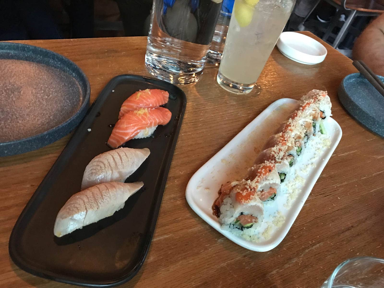 Two long rectangular plates with sushi served on them. One has nigiri with fish slices on top, and the other has intricately assembled rolls of sushi.