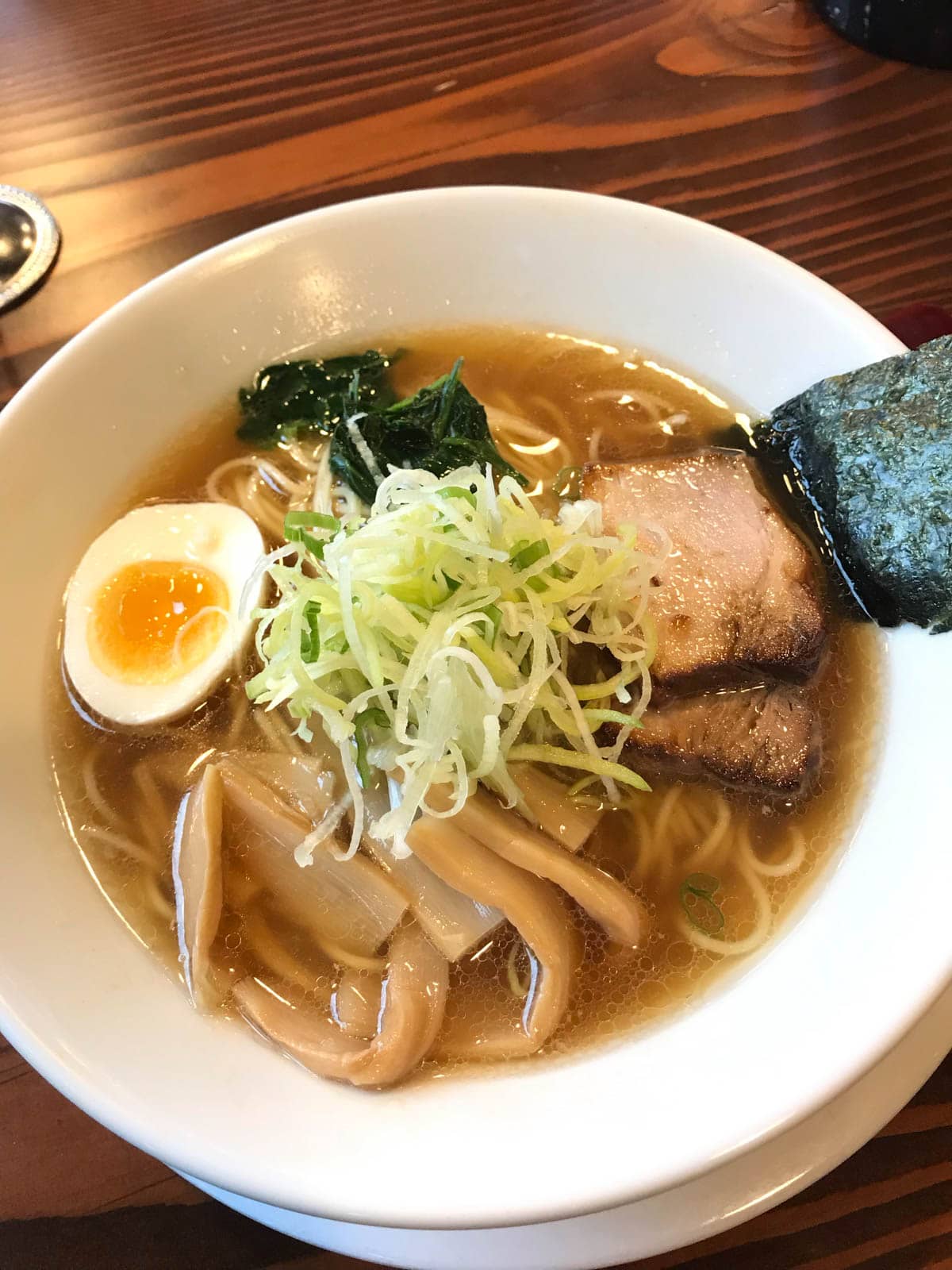 A bowl of ramen, with bamboo, pork, an egg, and dried seaweed