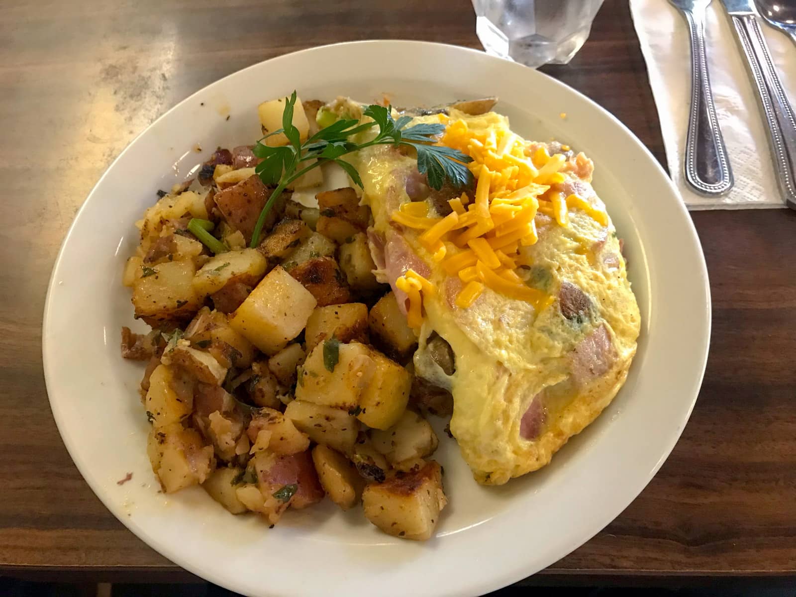 An omlette with ham, served alongside roast potatoes and topped with American cheese.