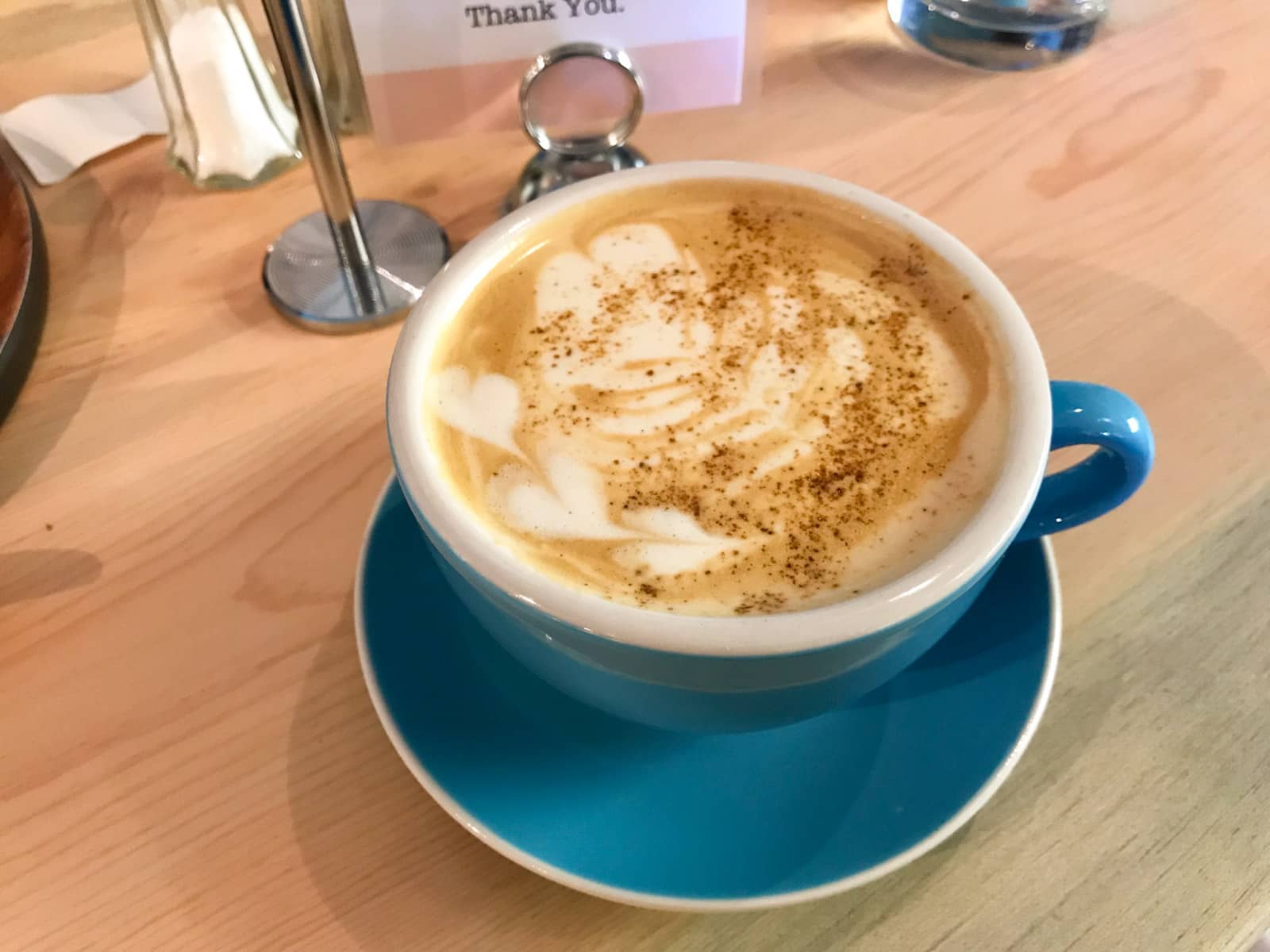 Chai latte served in a blue cup and saucer, with a sprinkle of cinnamon