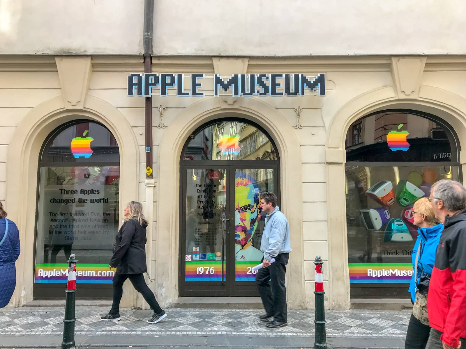 Three arched windows, above which reads a sign “Apple museum”. In the windows is rainbow-coloured signage and the Apple logo