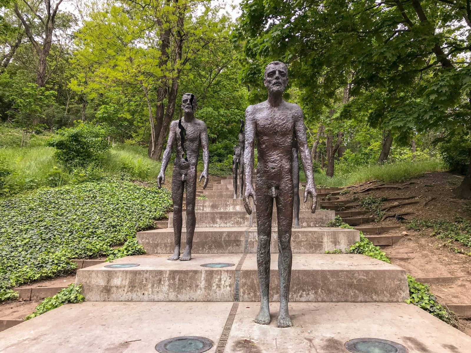 A memorial consisting of figures of people descending stairs, showing some more decayed than others