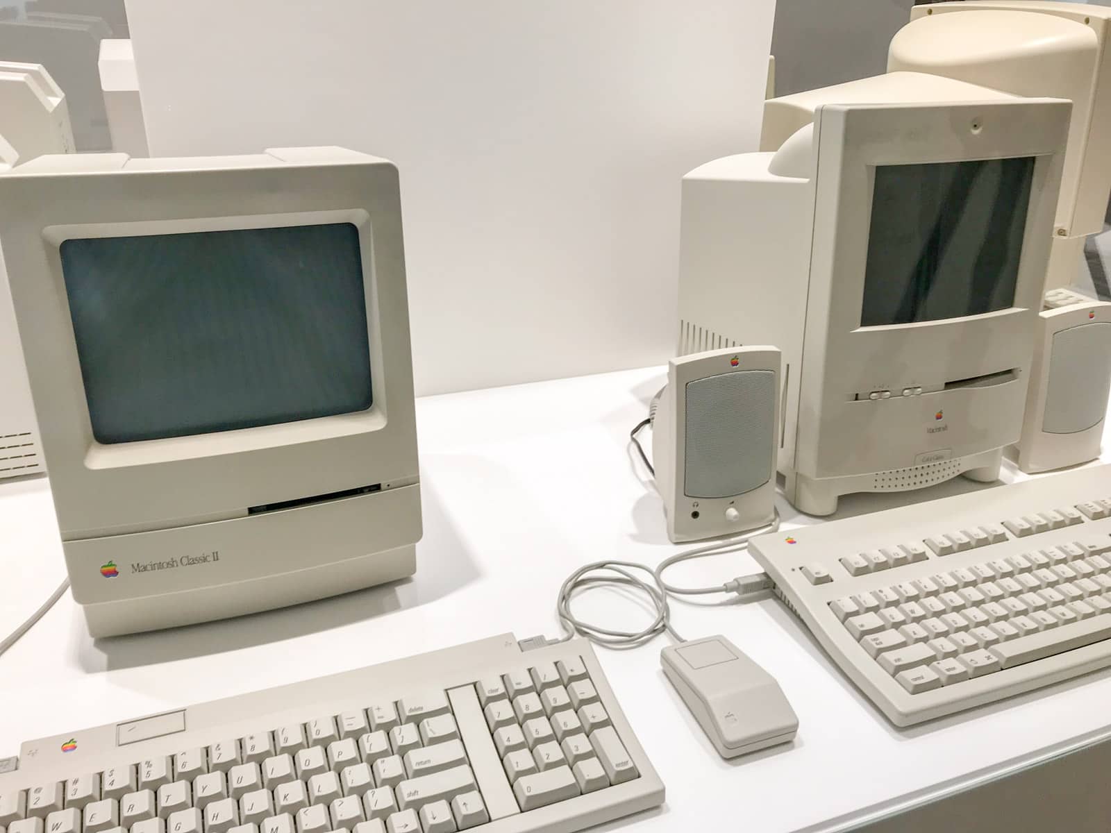 Two computer displays side by side, with keyboards in front of them. The hardware is light stone grey and the displays have very wide bezels