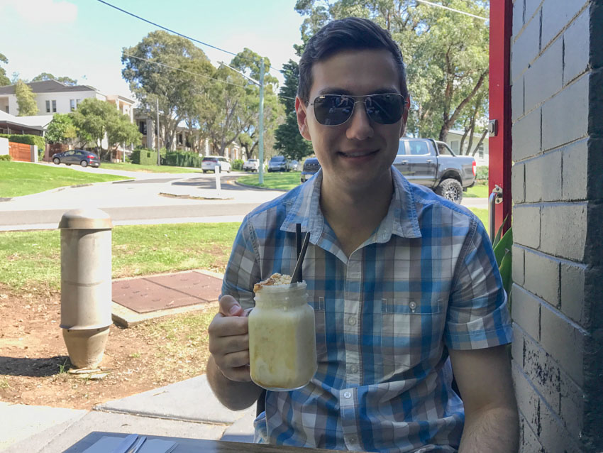 Nick holding his jar with a handle containing his drink, the streets in the background