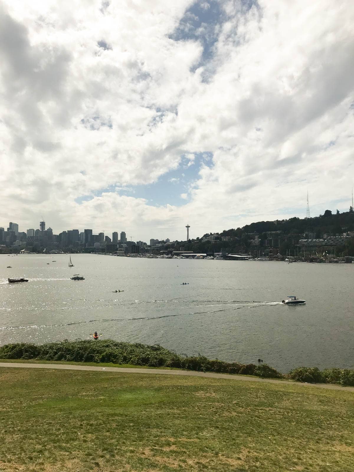 A view of the city of Seattle across Lake Union in the foreground, and a motor boat speeding past from the left to the right