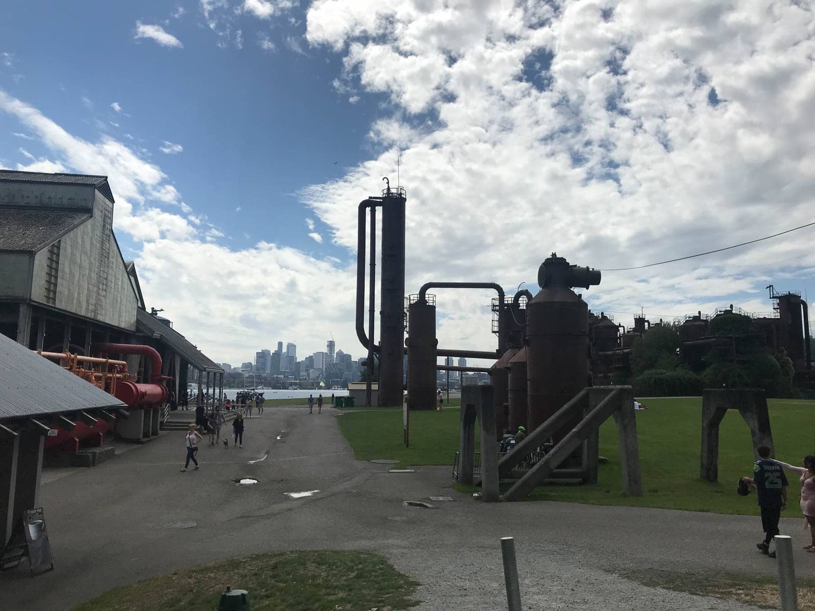 Remnants of a coal plant and some old buildings as part of a park. Way into the distance, the skyline of Seattle can be seen