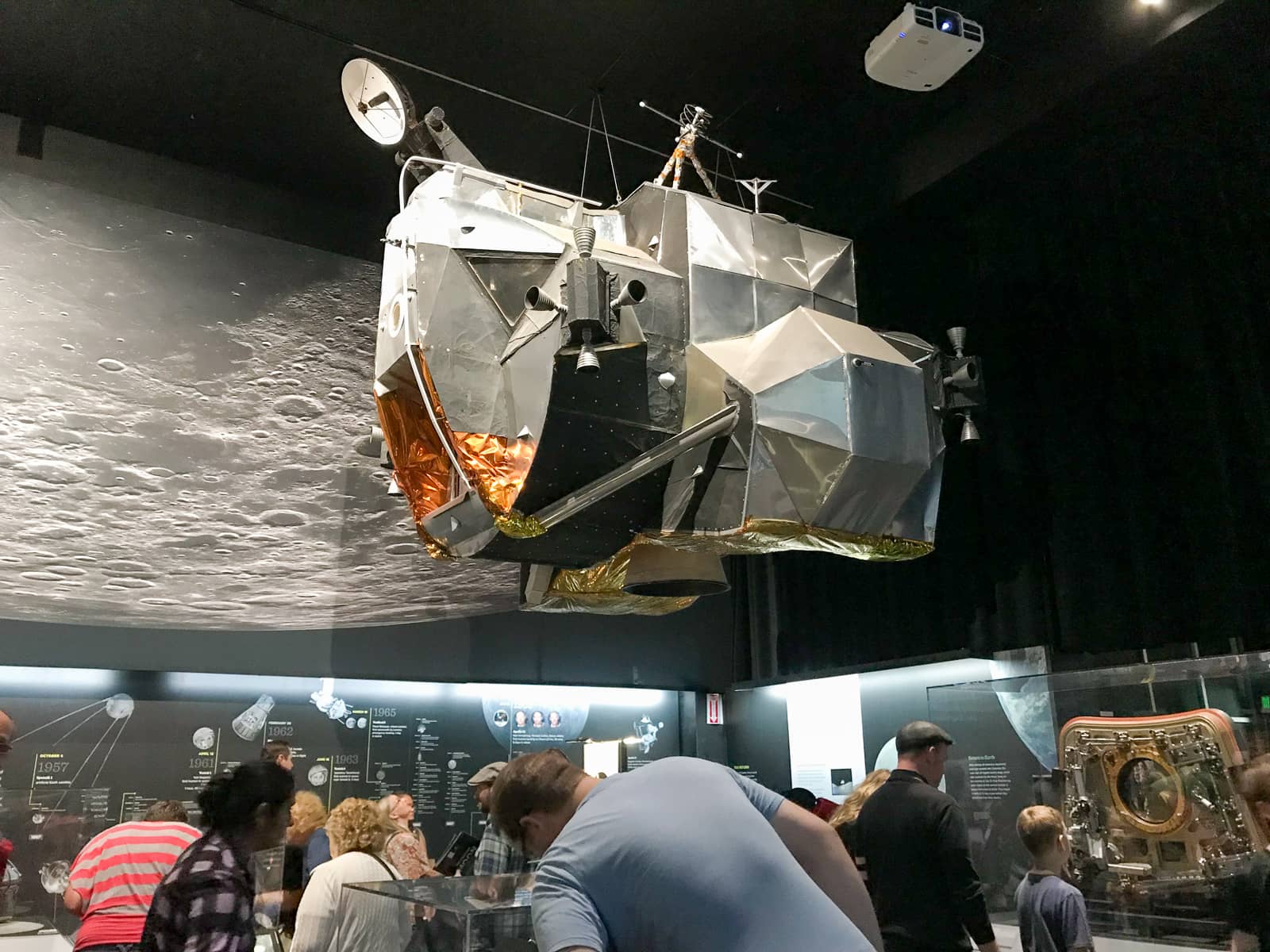 A giant metal structure hanging from the ceiling of a museum exhibition