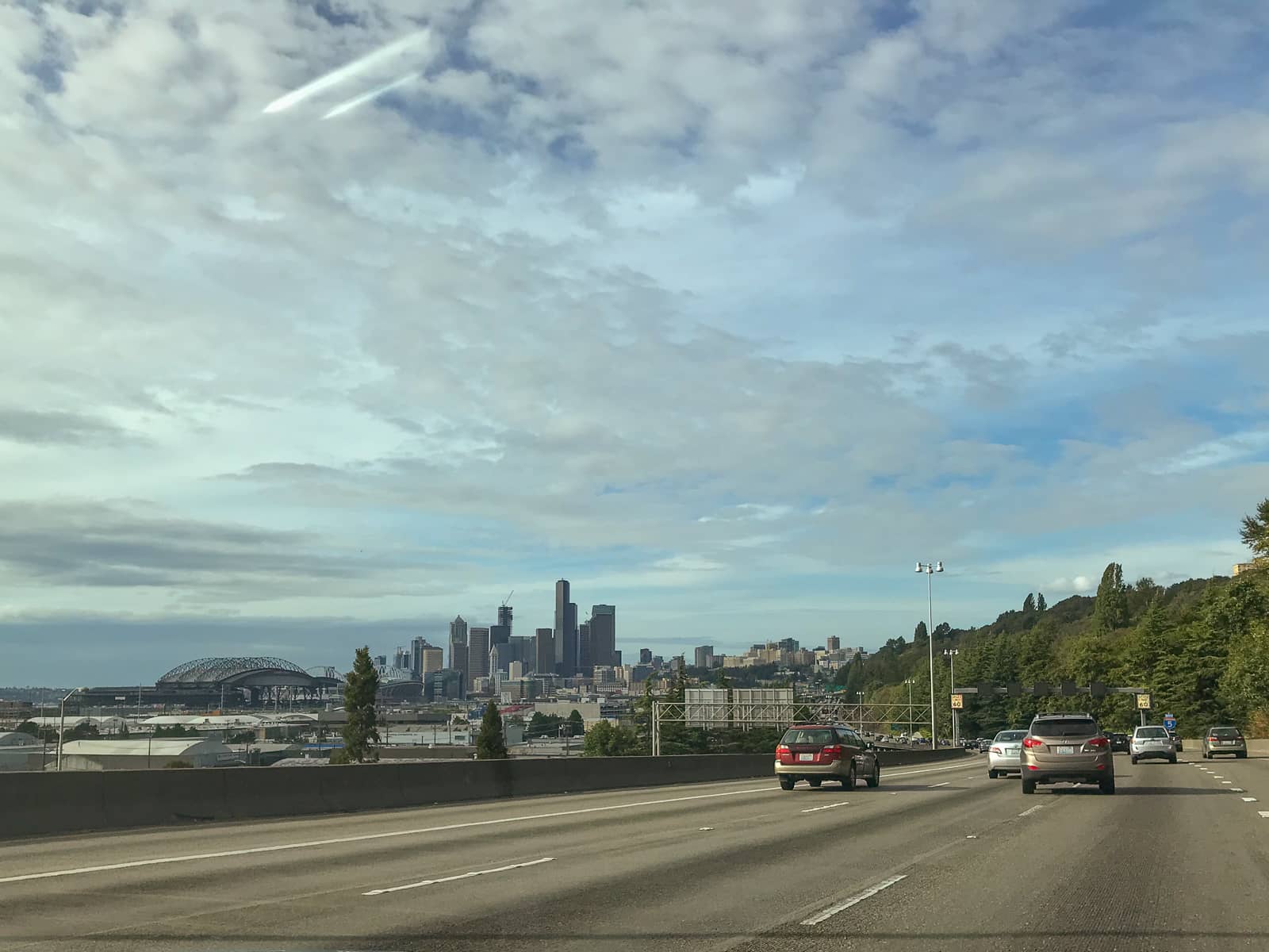 A view from a highway with several cars, of the skyline of the buildings in downtown Seattle