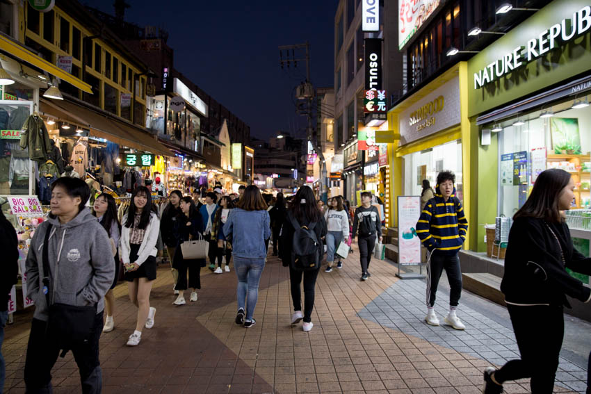 A view of the crowds down another street with fashion and skincare stores