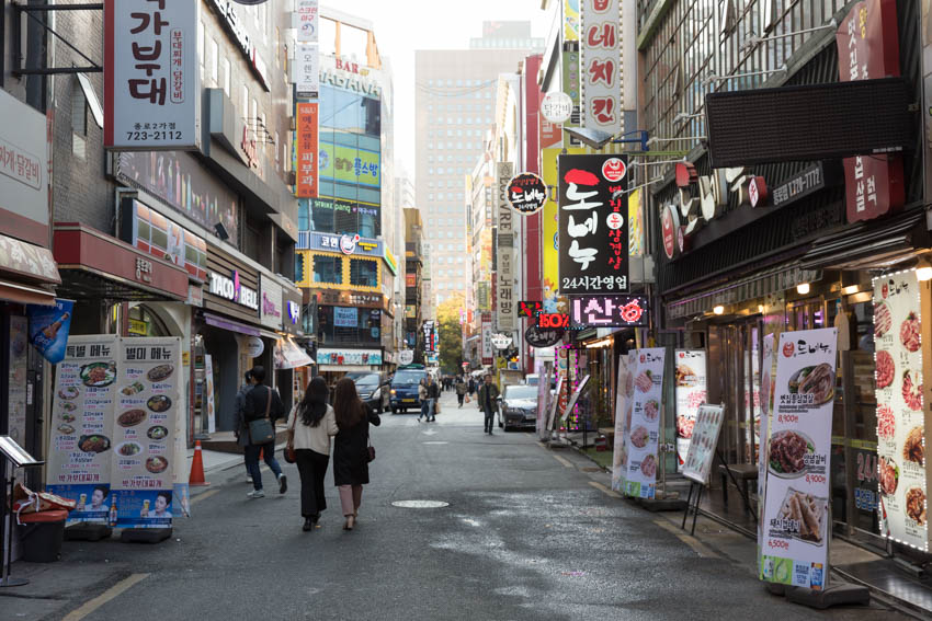 A street of eateries with their banners out front, advertising their products