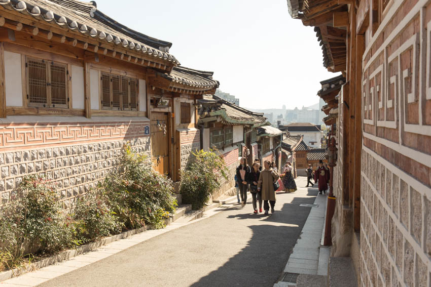 A slightly side-on view of people walking up an incline in a street