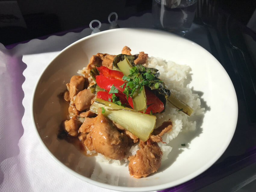 A white bowl filled with white rice, green vegetables and pieces of cooked chicken