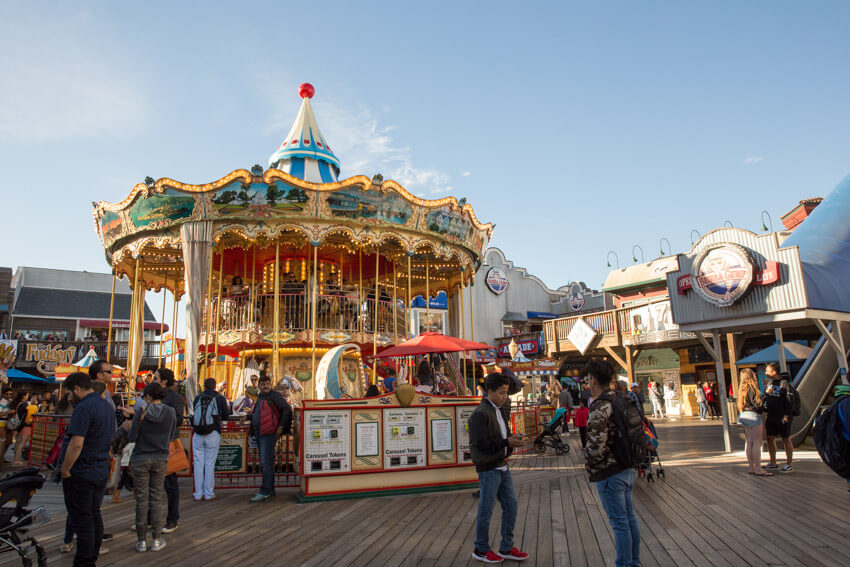 A large carousel on a pier, with a Bubba Gump restaurant in the background