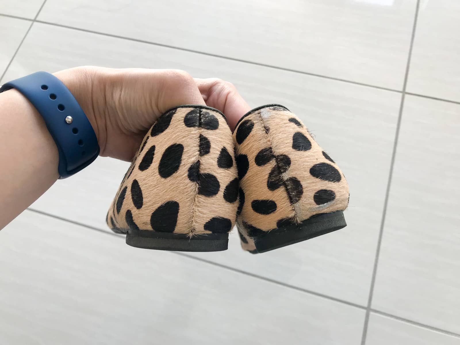 A close-up of the recently repaired heels of a pair of shoes, sand-coloured with a giraffe spot pattern