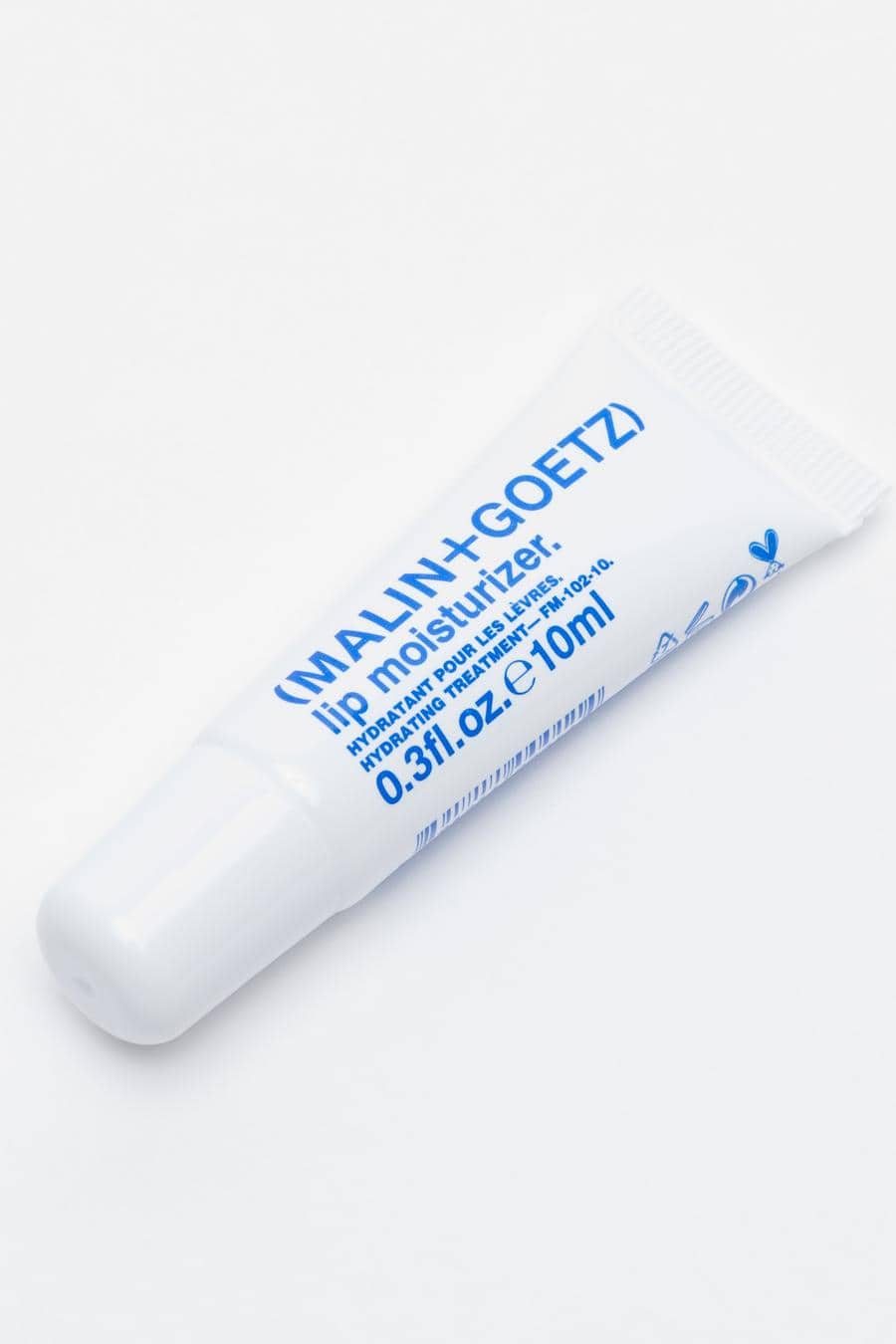A white tube of lip balm with blue text, reading “Malin + Goetz lip moisturiser”.