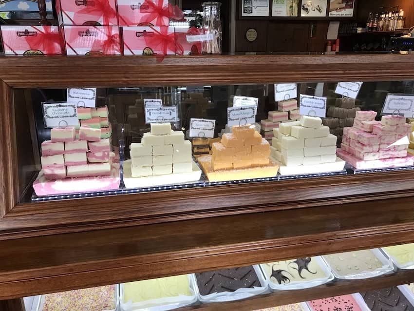 A small glass display in a store, showing various flavours of fudge.