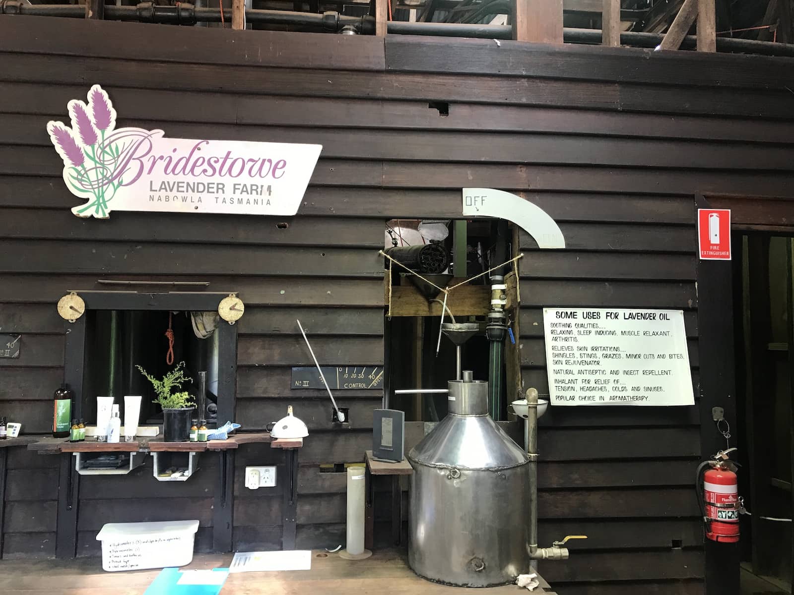 The interior of a distillery with a sign showing “Some uses for lavender oil” and some machinery in the foreground