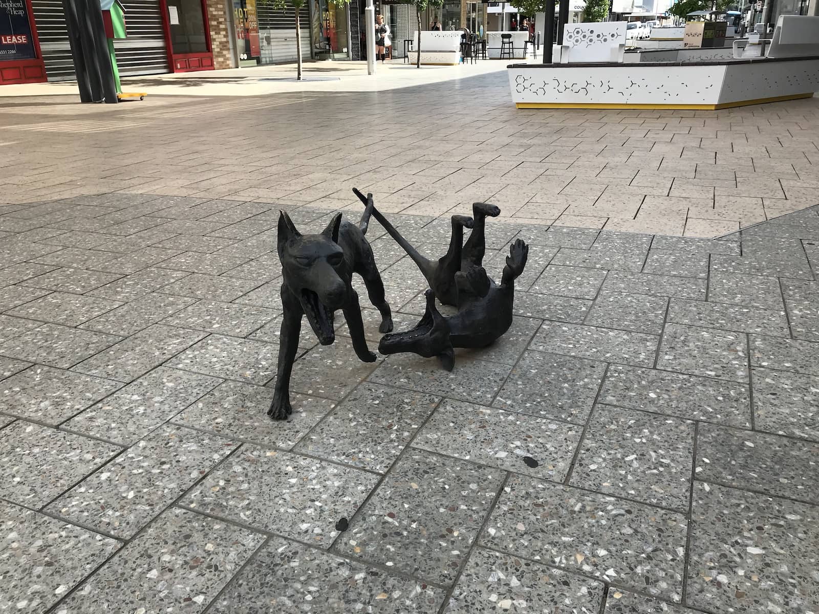 Small black sculptures, resembling the Tasmanian devil, on a concrete path