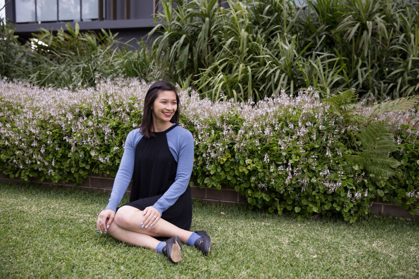 The same woman from the previous picture, in the same clothes and same setting. She is smiling wide and has her hands resting on her thighs and knees.