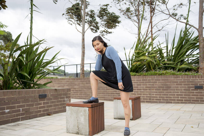 The same woman in the previous photo, with her right leg propped up on a concrete cube. She is leaning on her hand that is propped up on the leg that is raised.