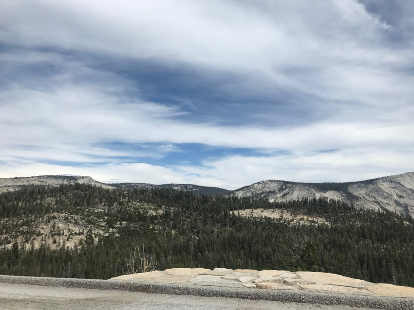 A mountainous view off the edge of a road, with many trees covering the landscape.