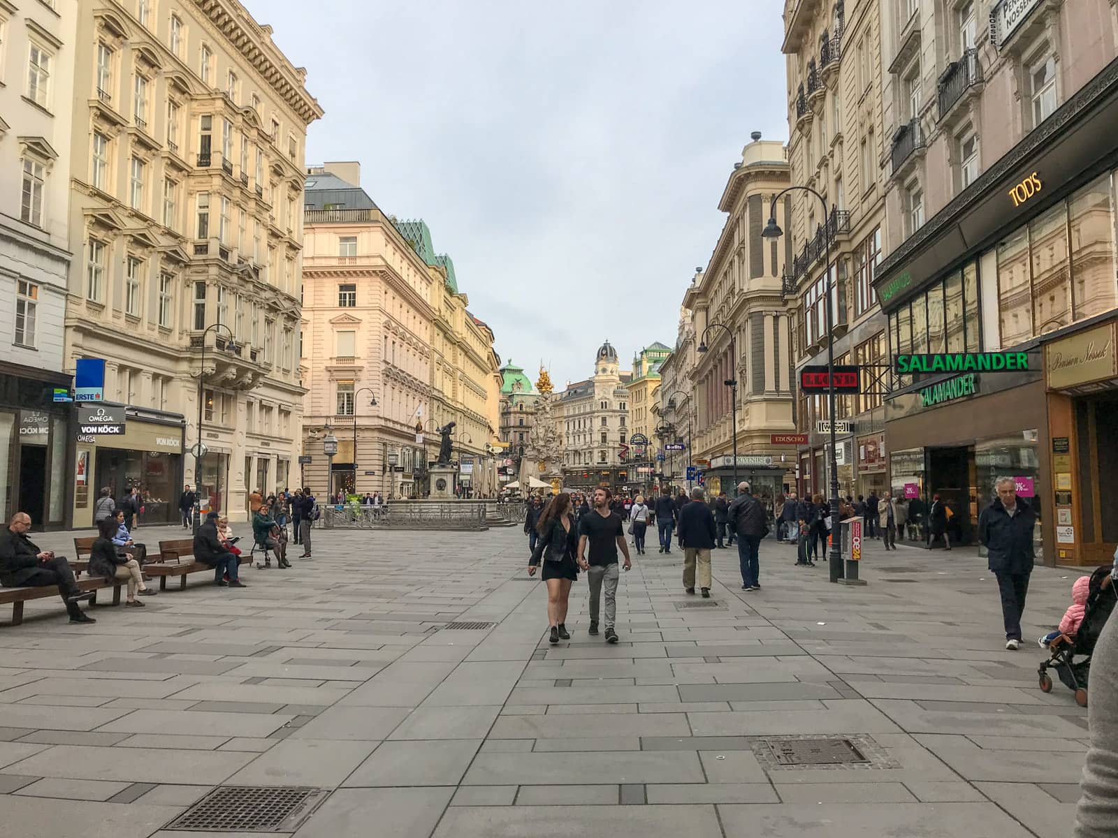 An outdoor shopping area in Vienna, in the late afternoon. People are walking through the mall