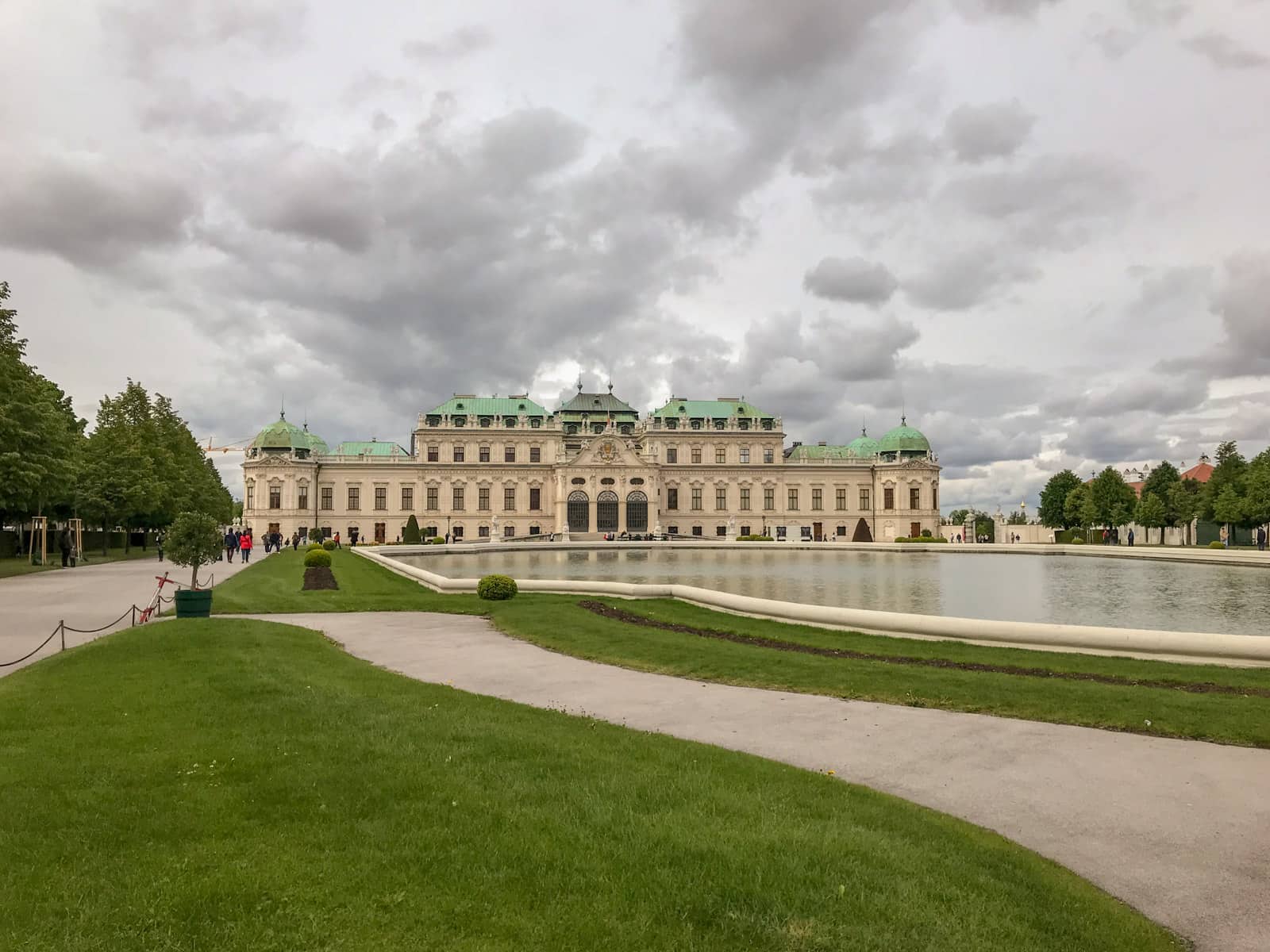 The grounds of Schlössgarten, showing an old, long building with green roofs. There is a man-made giant pond in front of it.