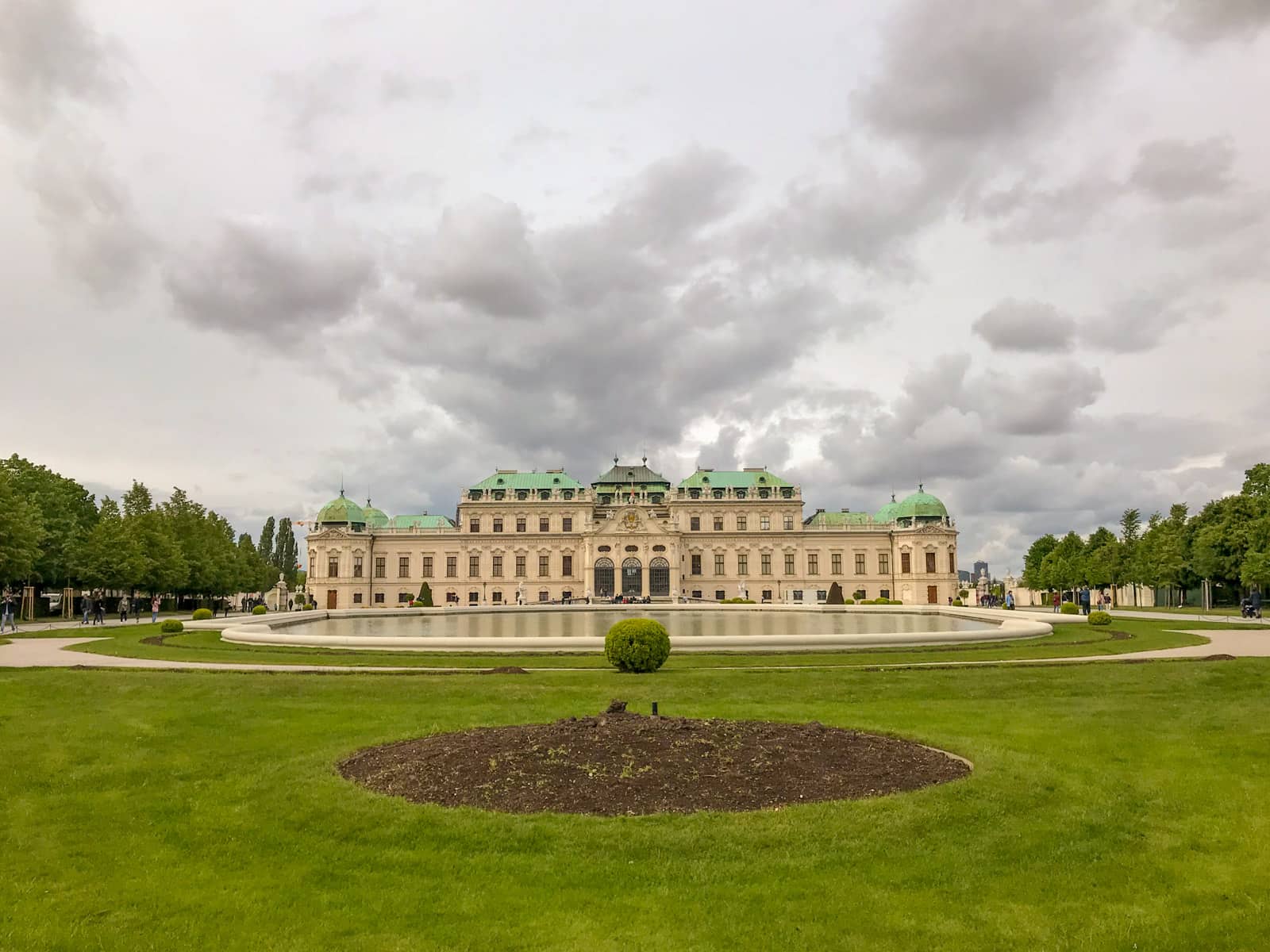 The grounds of Schlössgarten, showing an old, long building with green roofs. There is a man-made giant pond in front of it.