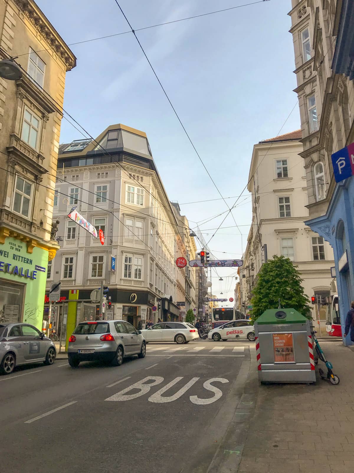 A view of a street in Vienna, in the late afternoon, showing an intersection that is going slightly uphill