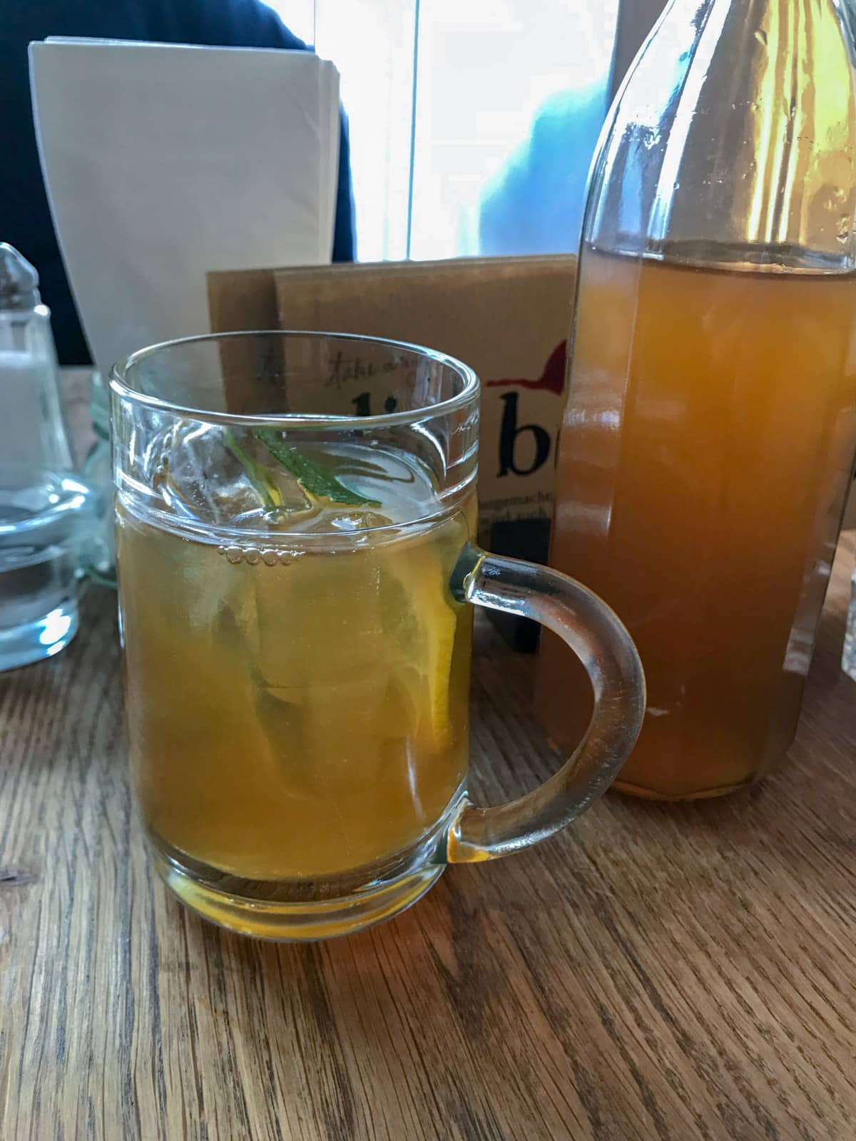 A glass mug with iced tea in it, next to a bottle of the same iced tea