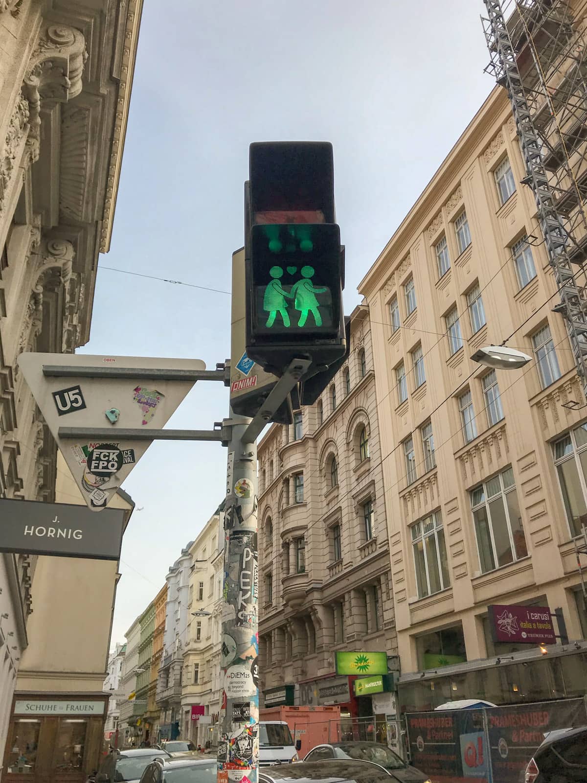 A pedestrian light, lit up in green, showing two female figures holding hands with a heart