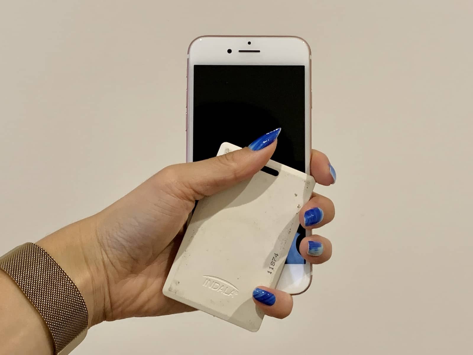 A woman’s hand holding a smartphone and white plastic card