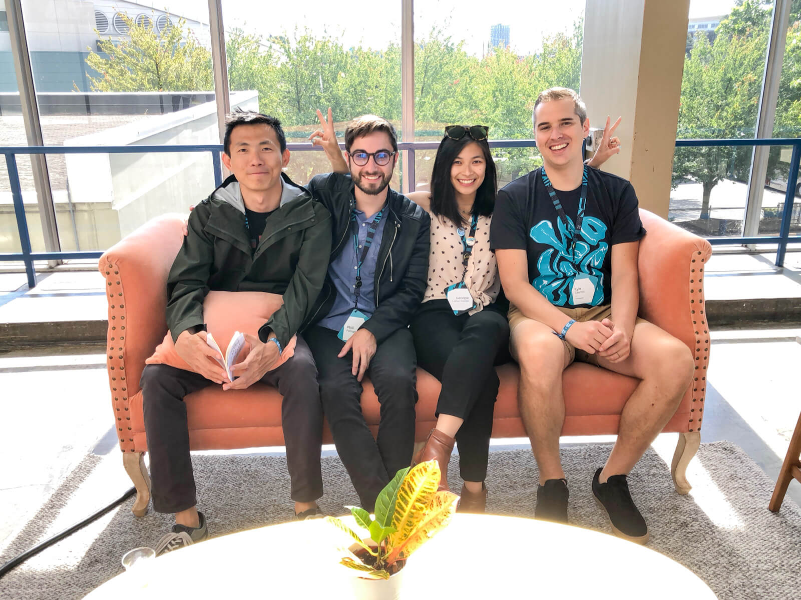 Three men and one woman sitting next to each other on a couch; they are all smiling