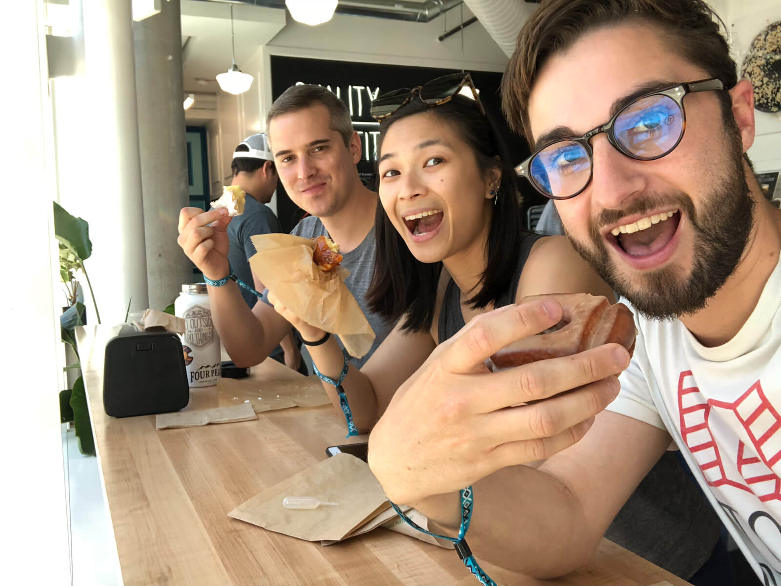 Three people smiling and holding doughnuts