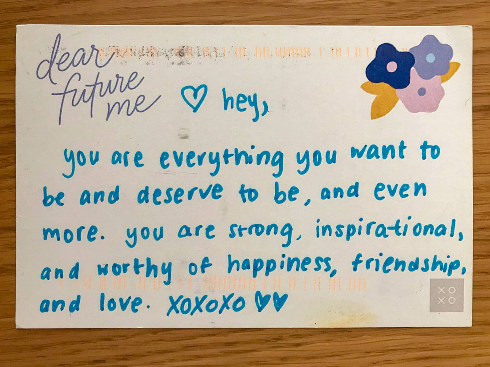 A postcard with “dear future me” printed on it and a handwritten message in blue ink: hey,
you are everything you want to be and deserve to be, and even more. you are strong, inspirational, and worthy of happiness, friendship and love. xoxoxo