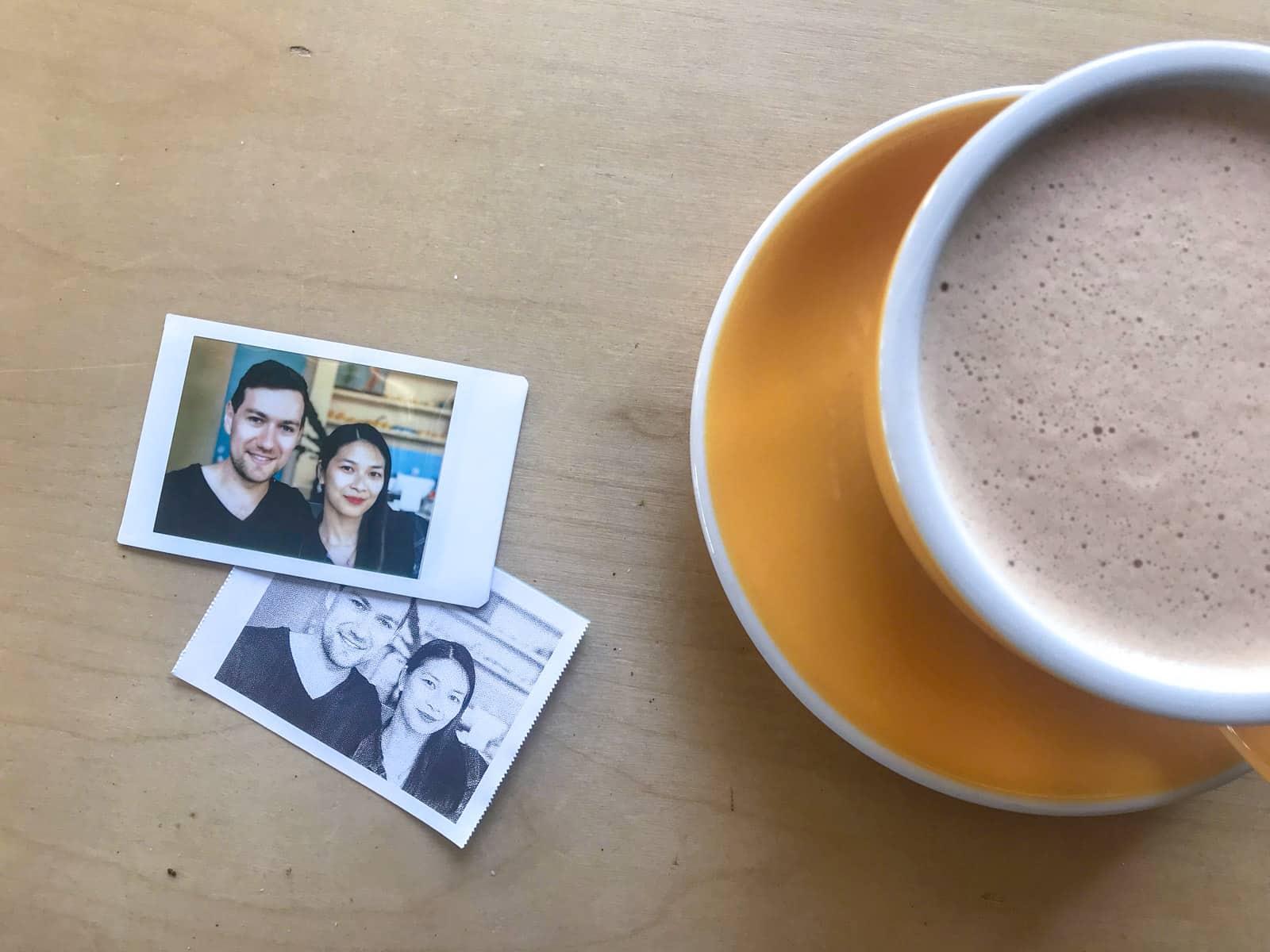 A photo of a woman and man printed onto a polaroid, next to a yellow cup of coffee