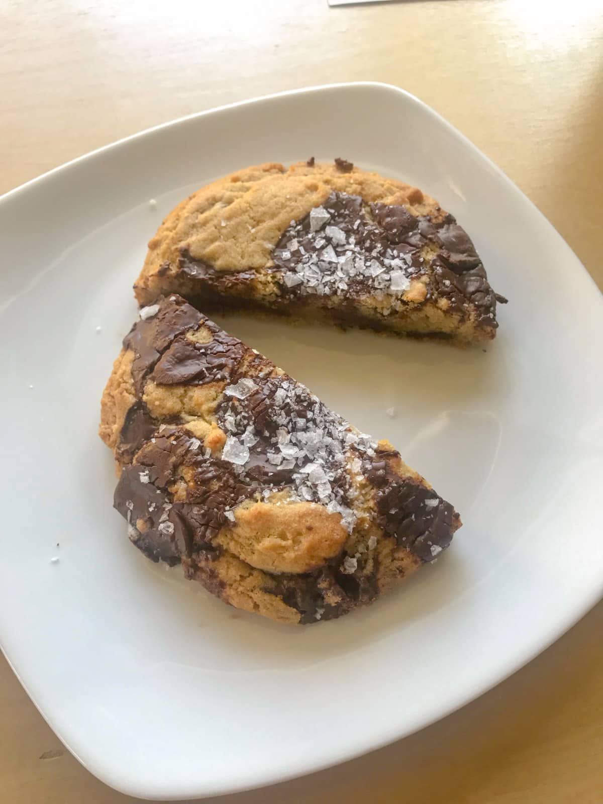 A chocolate chip and sea salt cookie on a plate, cut in half