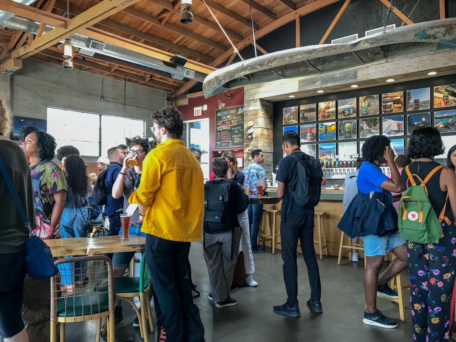 A brewery with a lot of natural lighting, with a small crowd of people standing around