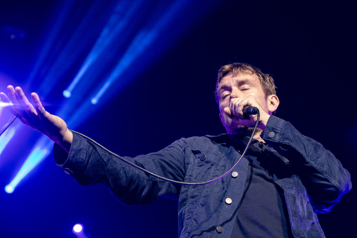 Damon singing with the microphone cable in his outstretched arm