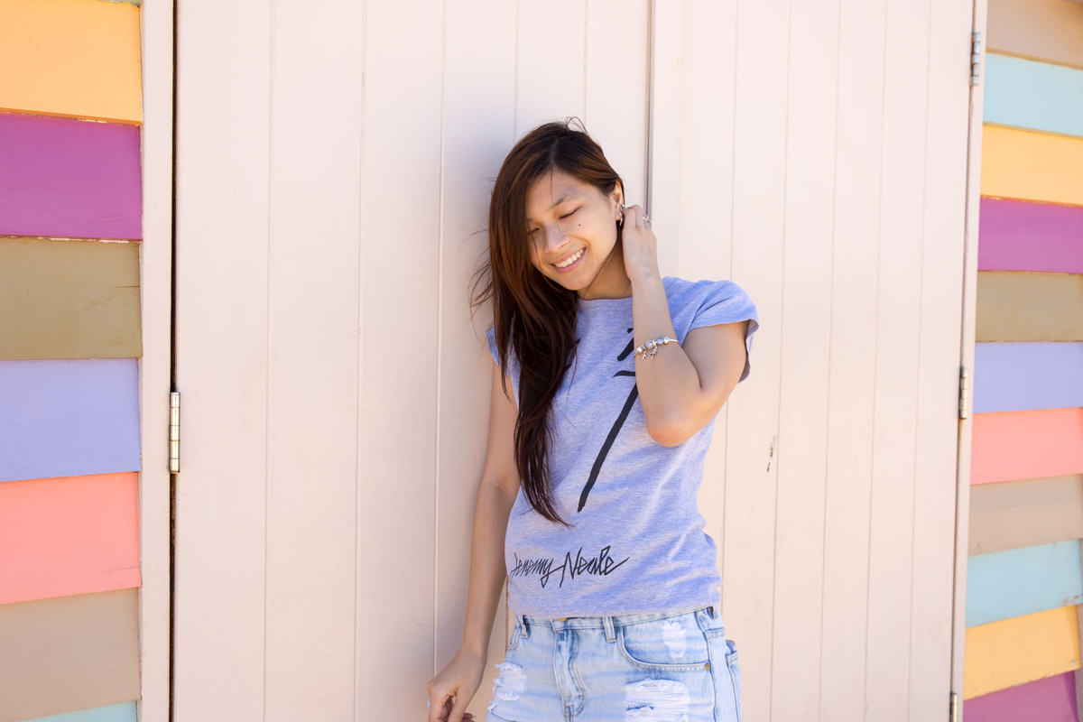 Girly, muted colours in the background as I lean against a pale coloured door